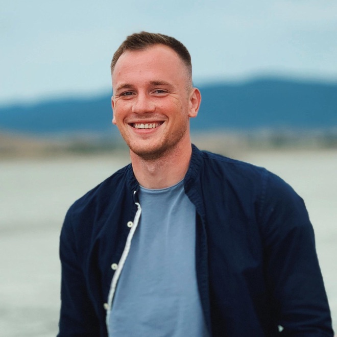 Denys smiling, leaning against a car on a dry lake bed